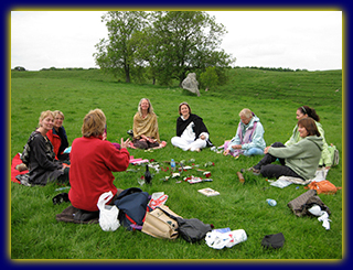 a group of people sitting on the grass and having a consensus process focalizing session